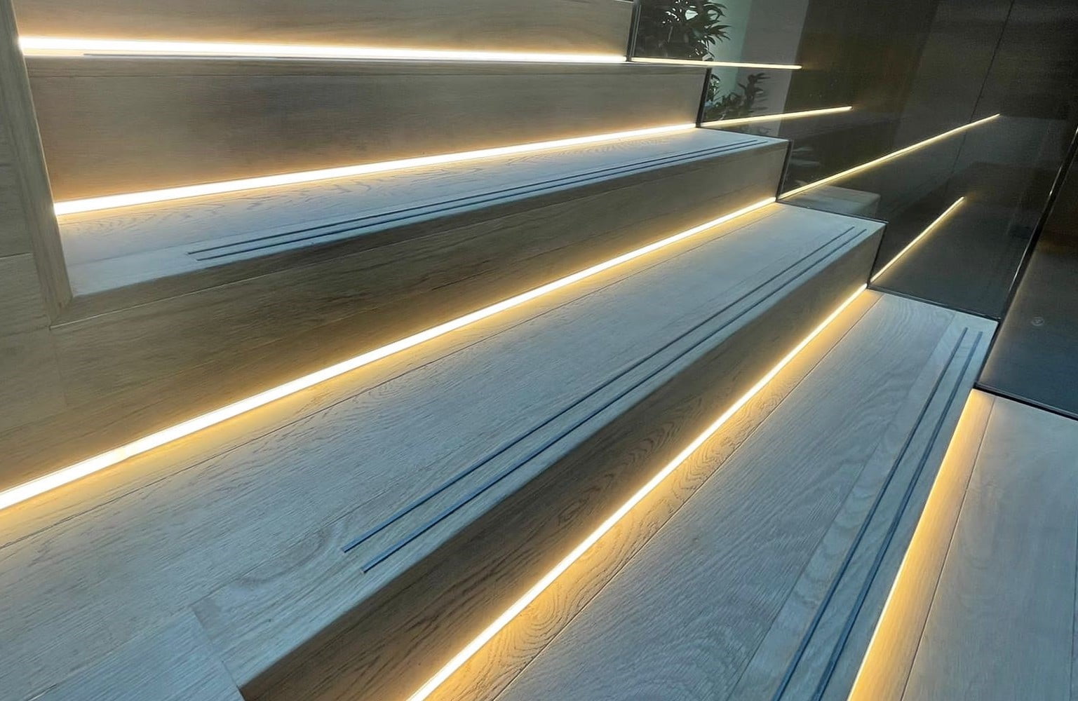 Aluminium Stair Tread Inserts on a light wood step with LED under step lights